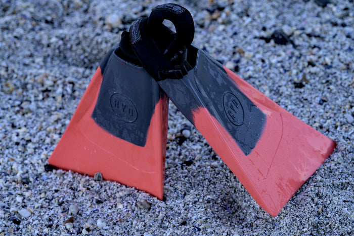 RYD Elo swim flippers in Coral resting on shell sand