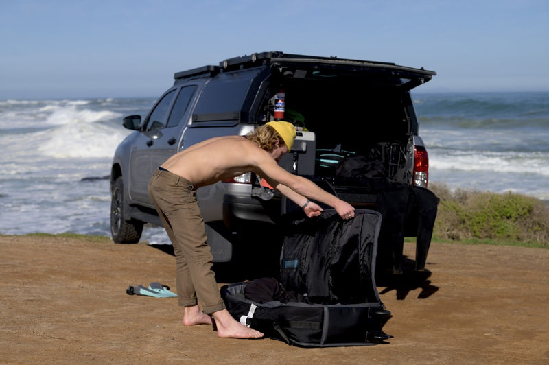 Unpacking an RYD Bodyboard Range Explore travel bag from the back of a bakkie
