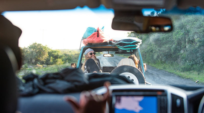 A Land Cruiser with two RYD Layback Range Everyday board covers strapped to the roof rack, heading to the beach