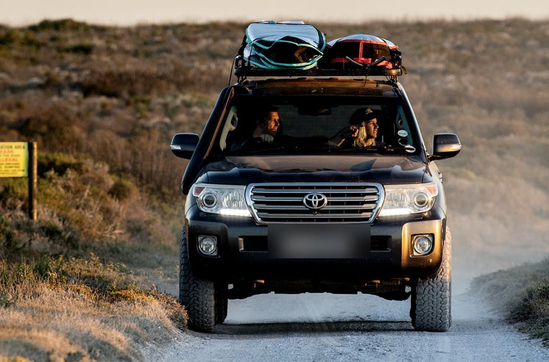 A driver with RYD Layback Range Explore board covers strapped to his Land Cruiser's roof rack