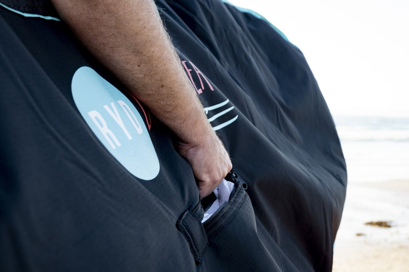 Close-up of someone carrying an RYD SUP Range Everyday board cover, showing the logo and zip pocket