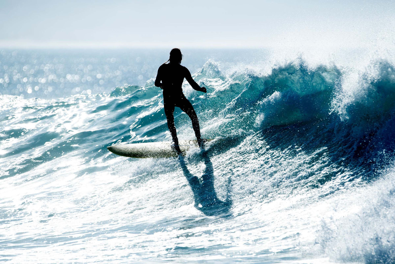 A surfer riding a green wave on a longboard, tucked low as the wave curls above